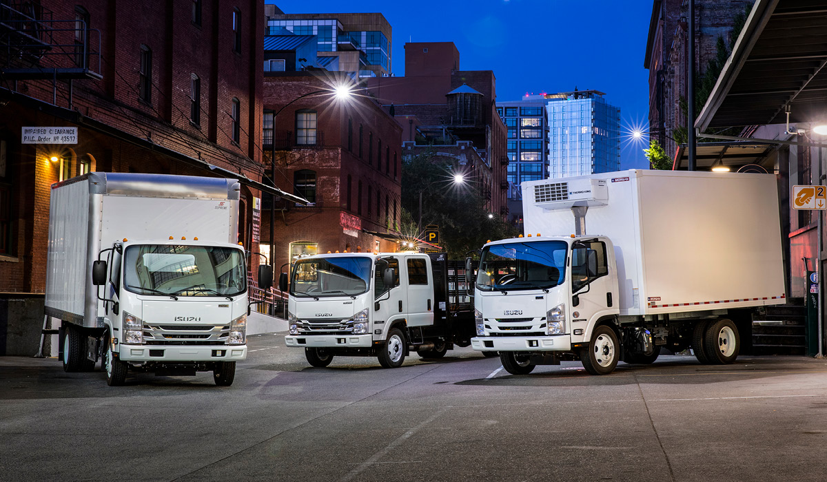 Photo of three Isuzu trucks at night