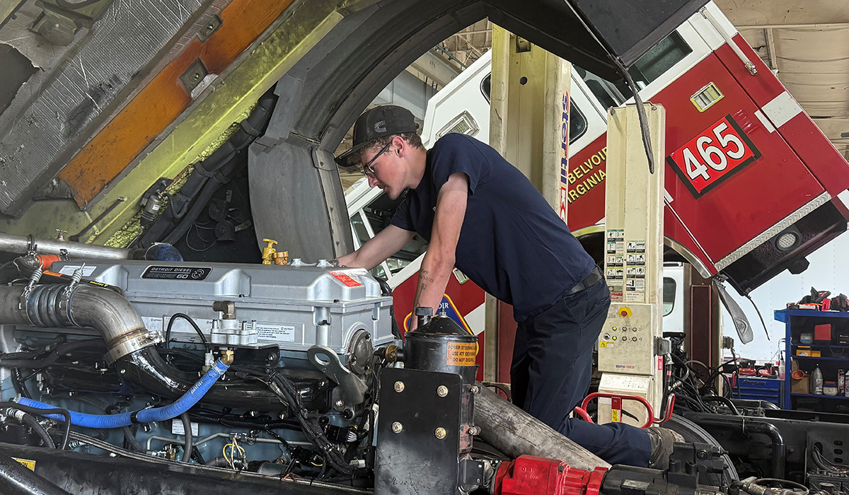 technician working under the hood of a truck.